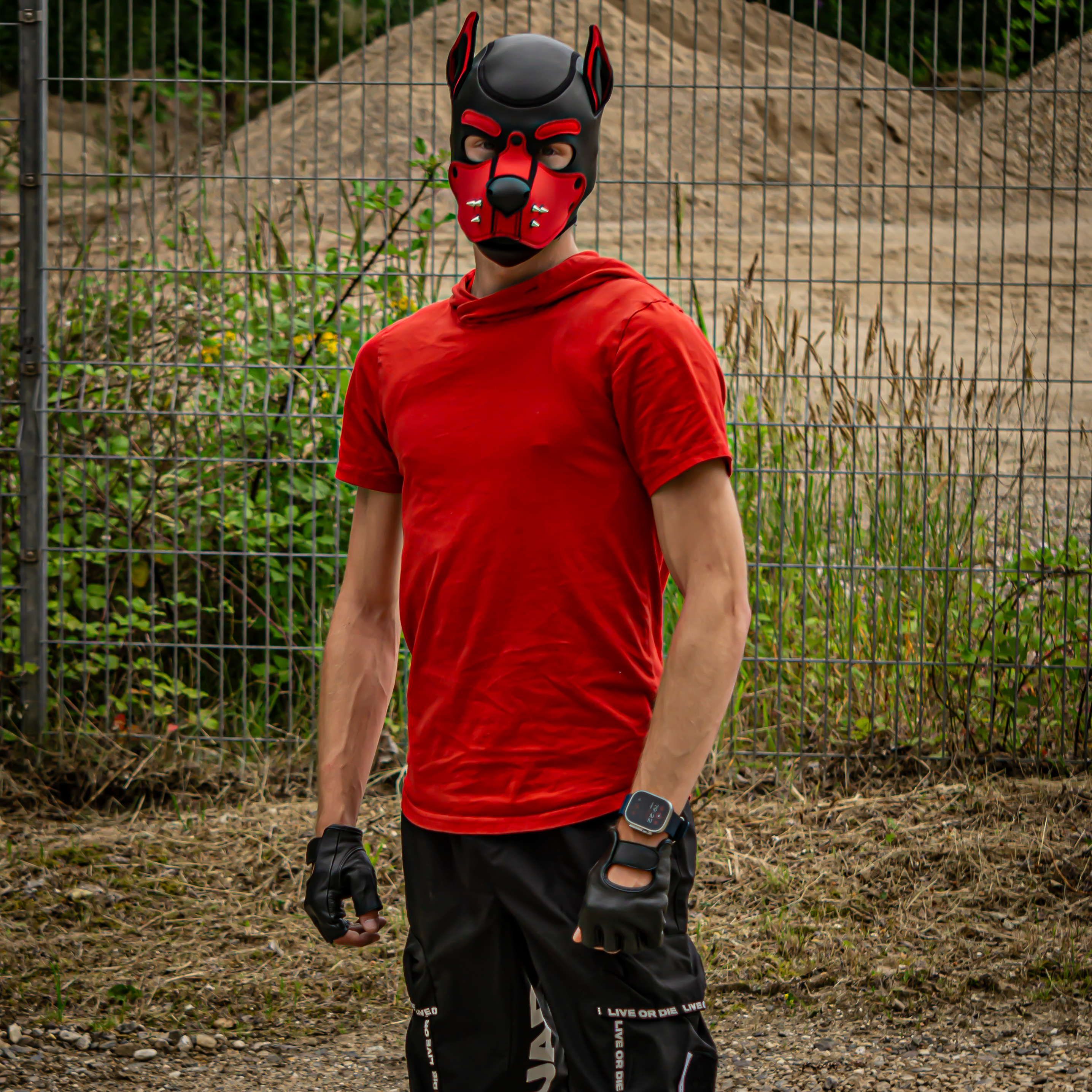 a man wearing a red shirt and black gloves with a dog mask