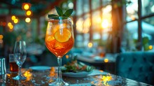 a glass of orange liquid with slices of orange and mint on a table