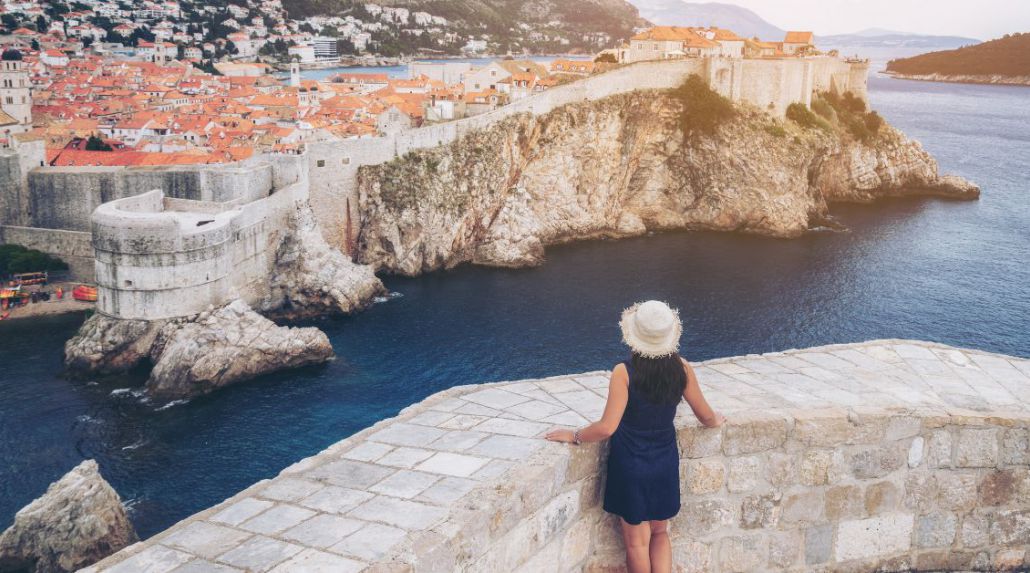 a woman standing on a stone wall overlooking a body of water