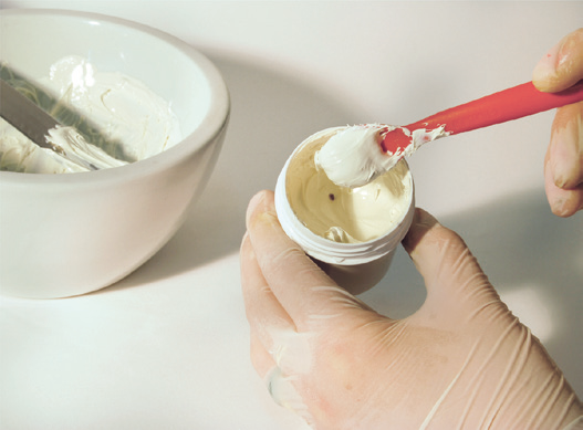 a hand holding a jar of white cream