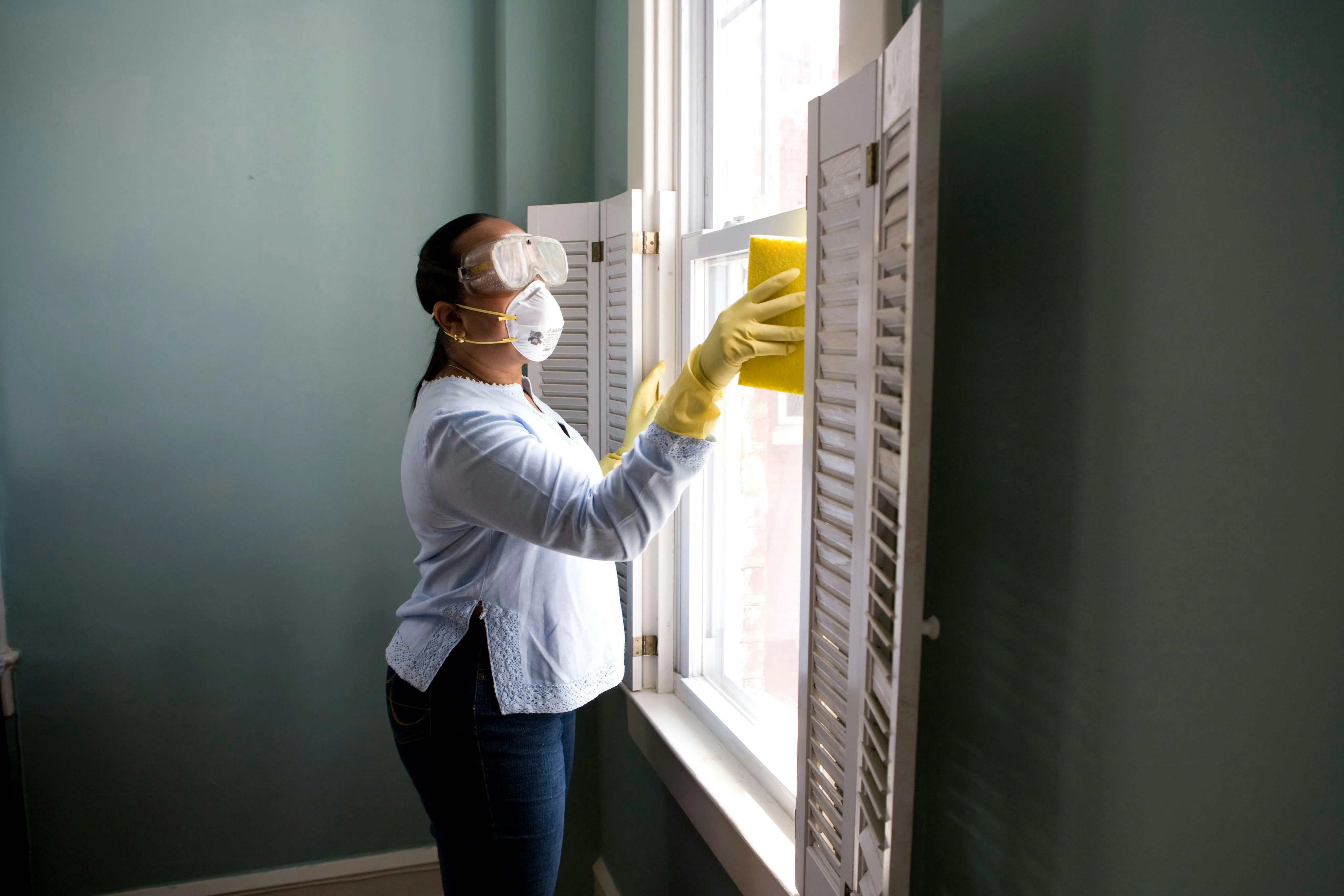 a woman wearing goggles and gloves cleaning a window