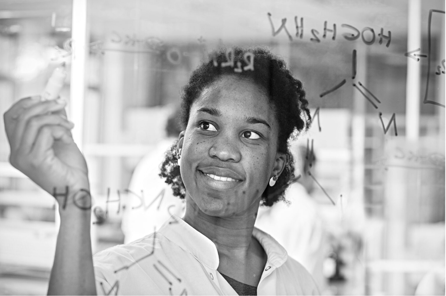 a woman writing on a glass board