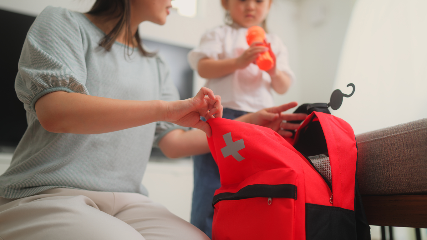 a woman putting a red backpack on a child's back