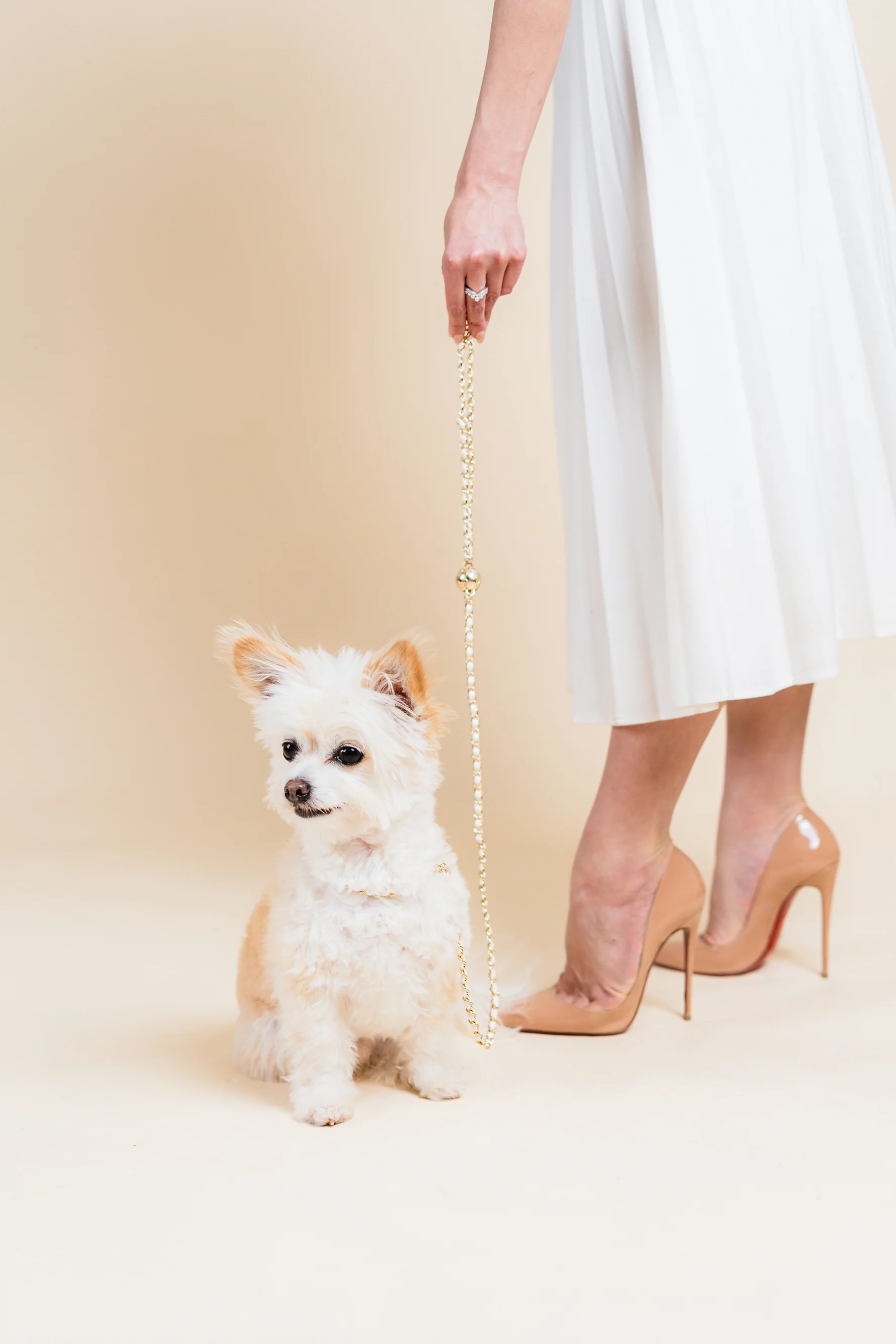 a woman in a white dress and high heels holding a dog leash