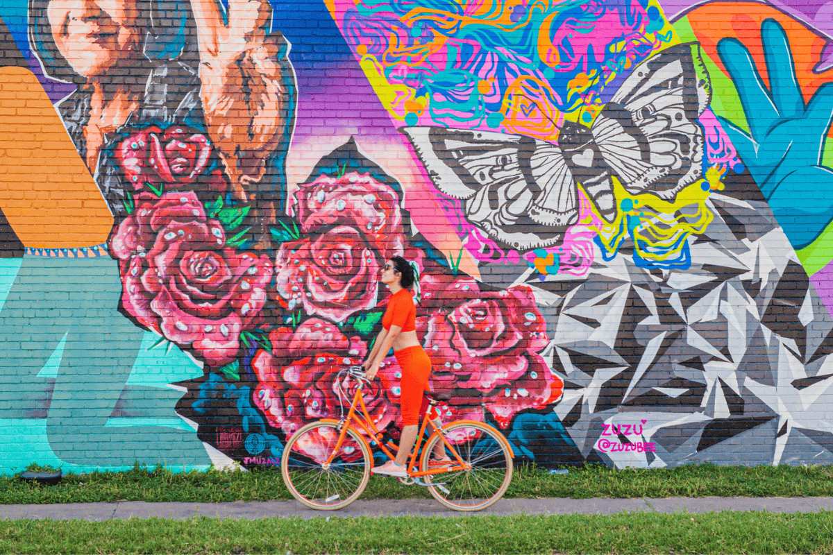 a woman riding a bike in front of a colorful wall