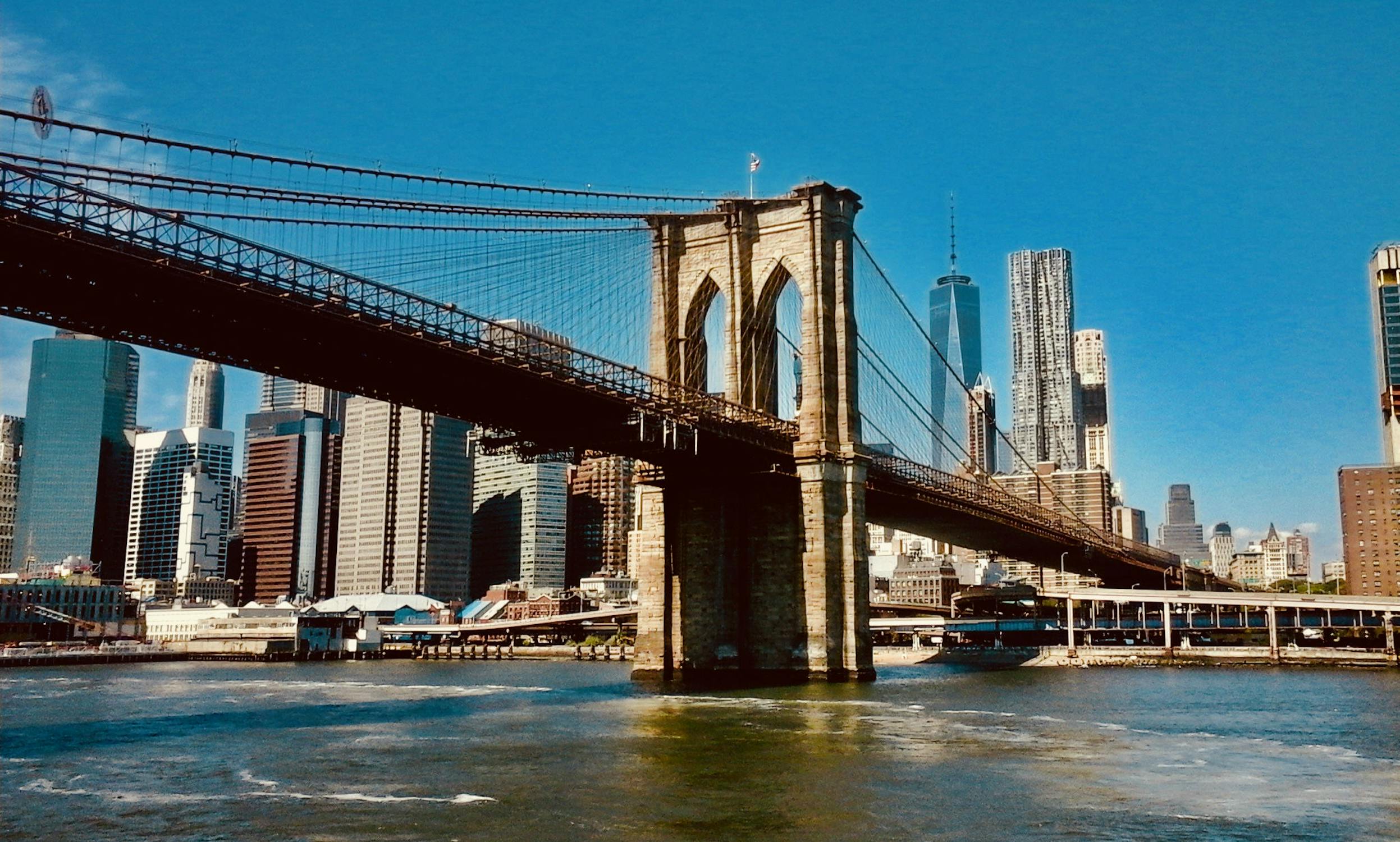 Brooklyn Bridge over water with a city in the background