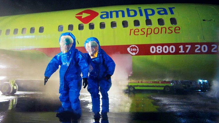 people in protective suits near a plane