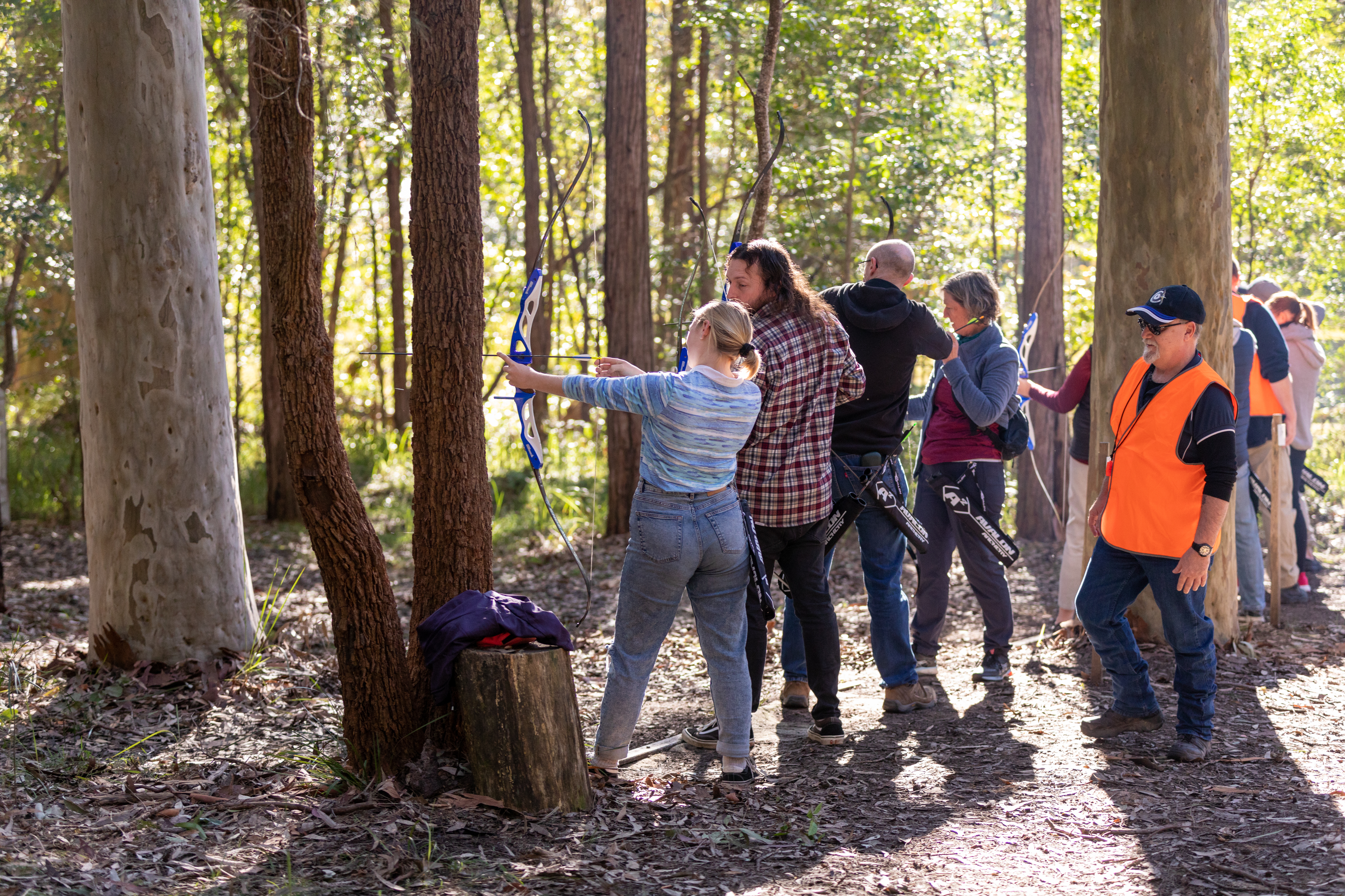 a group of people shooting bows in the woods