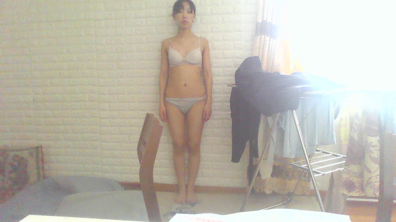 a woman in underwear standing in front of a white wall