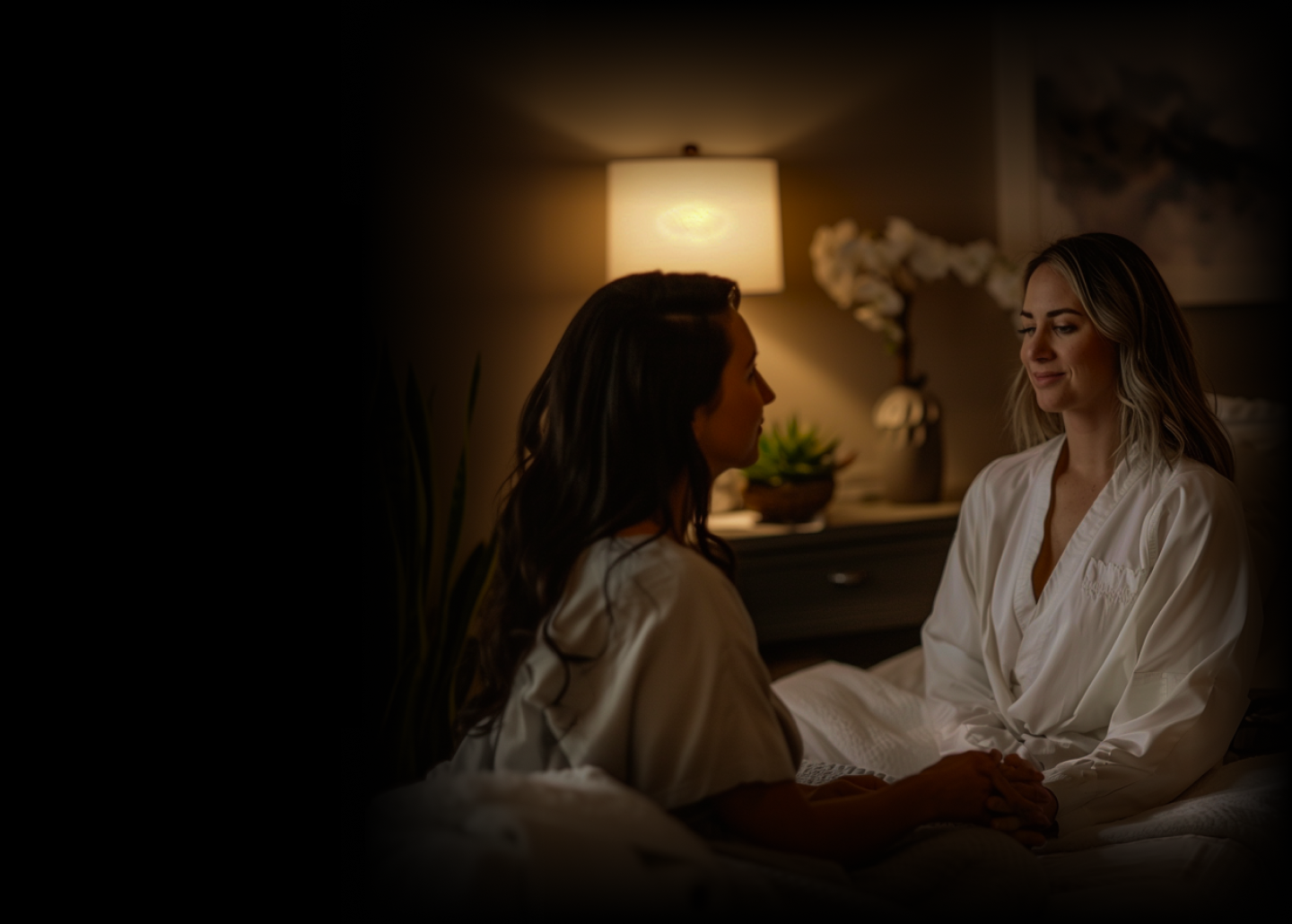 a couple of women in white robes sitting on a bed