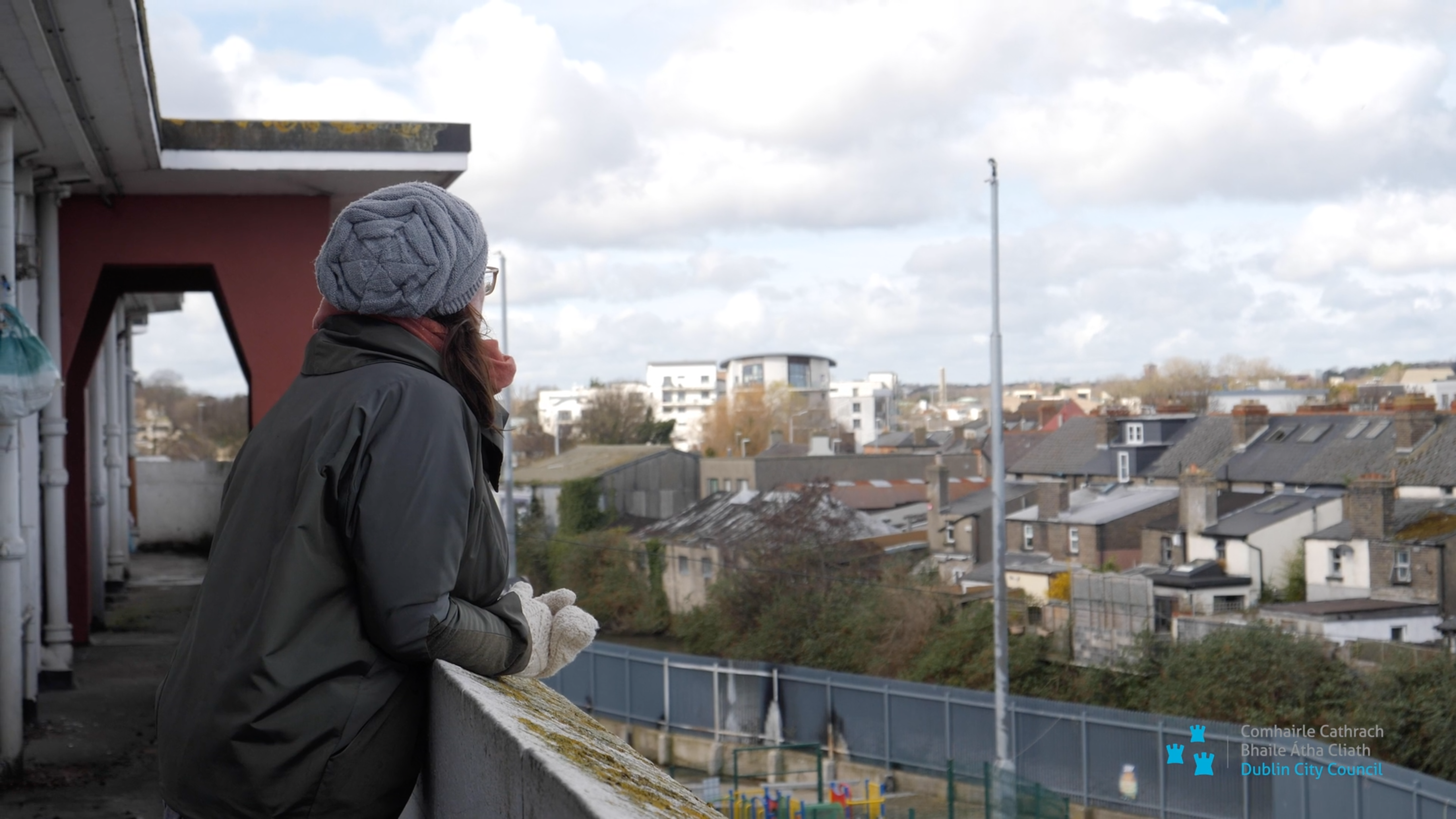 a woman leaning on a ledge looking out over a city