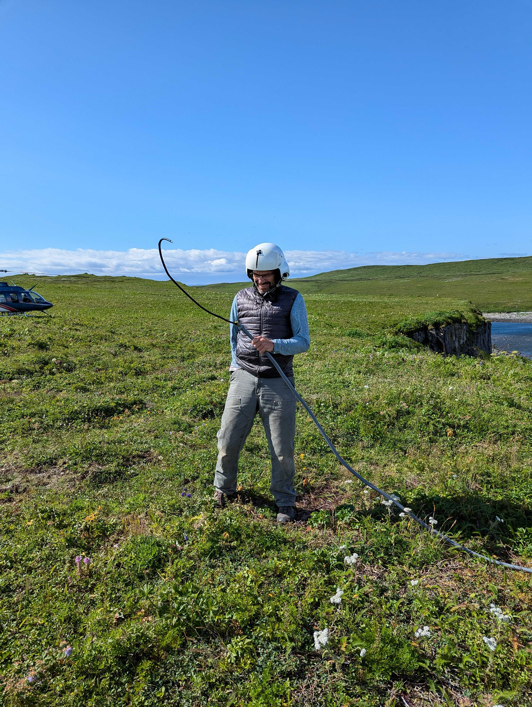 a man in a white helmet holding a rope in a grassy field