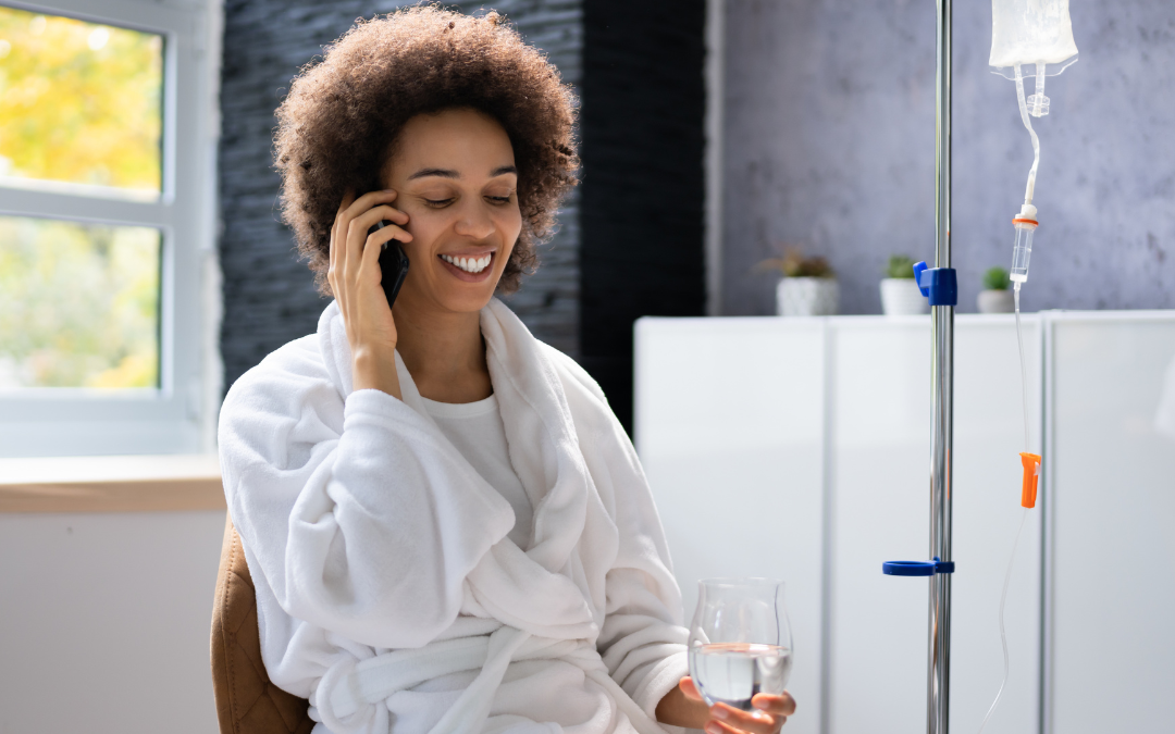 a woman in a bathrobe holding a glass and talking on a cell phone