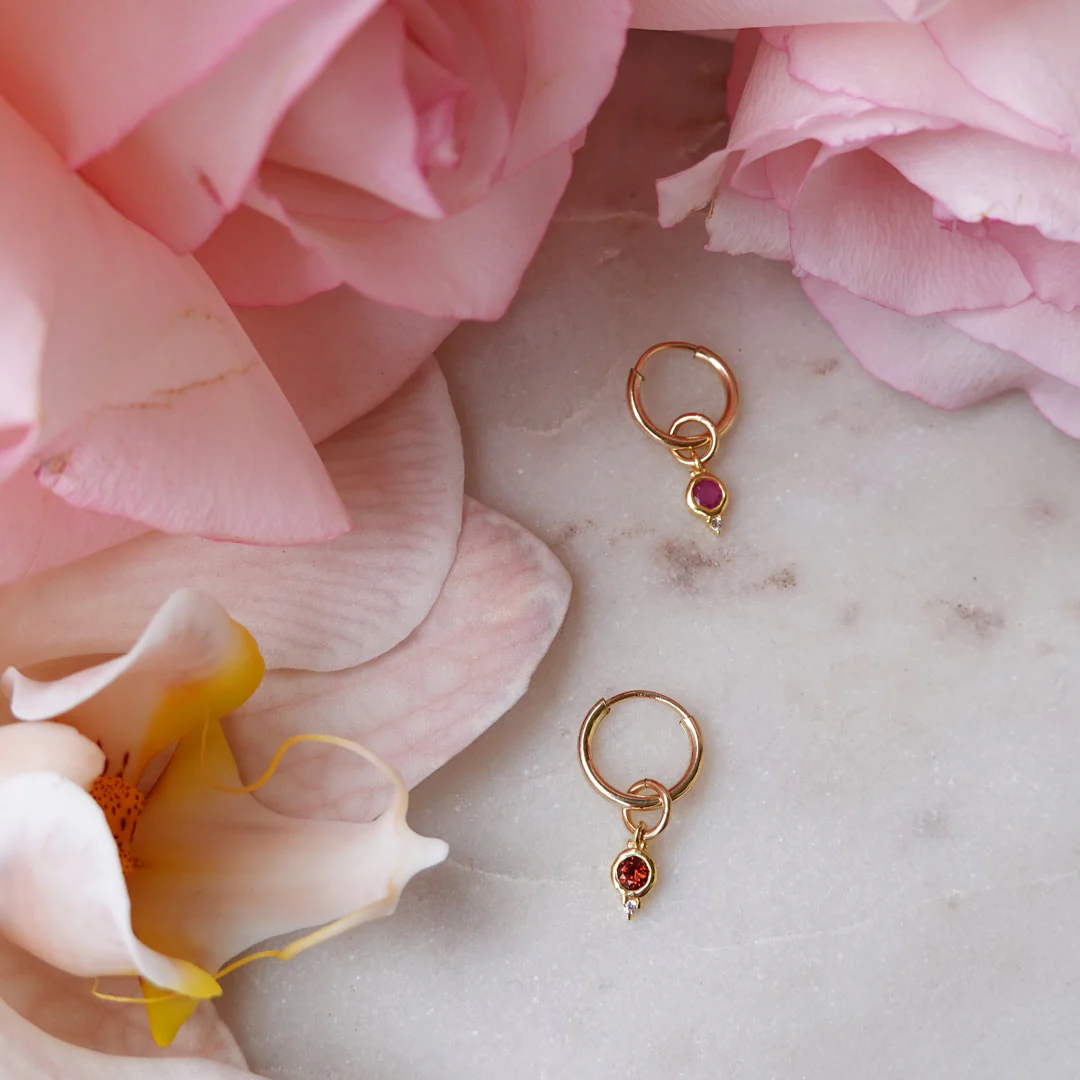 a pair of gold earrings with gems on top of pink flowers