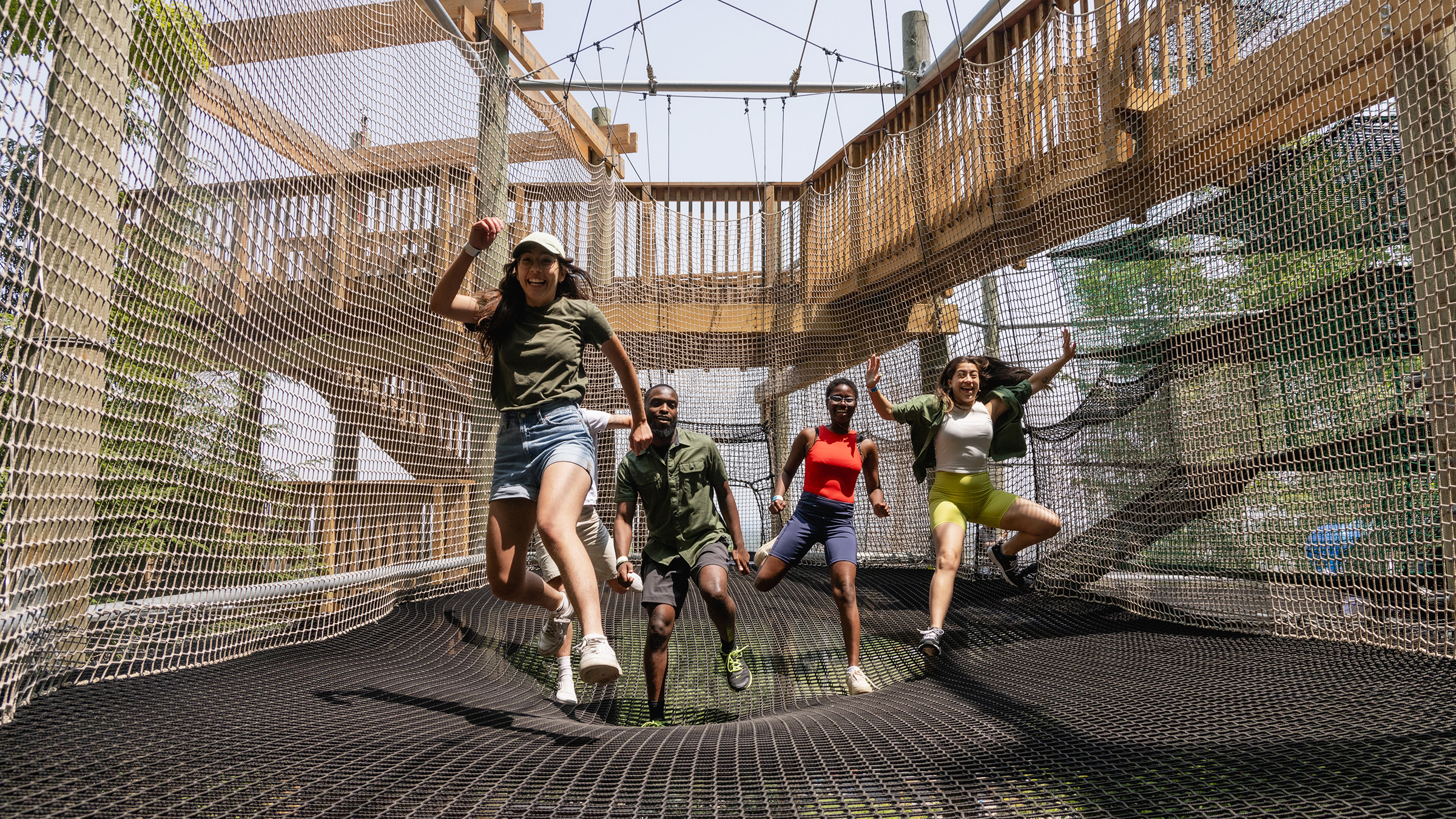 a group of people jumping on a rope bridge