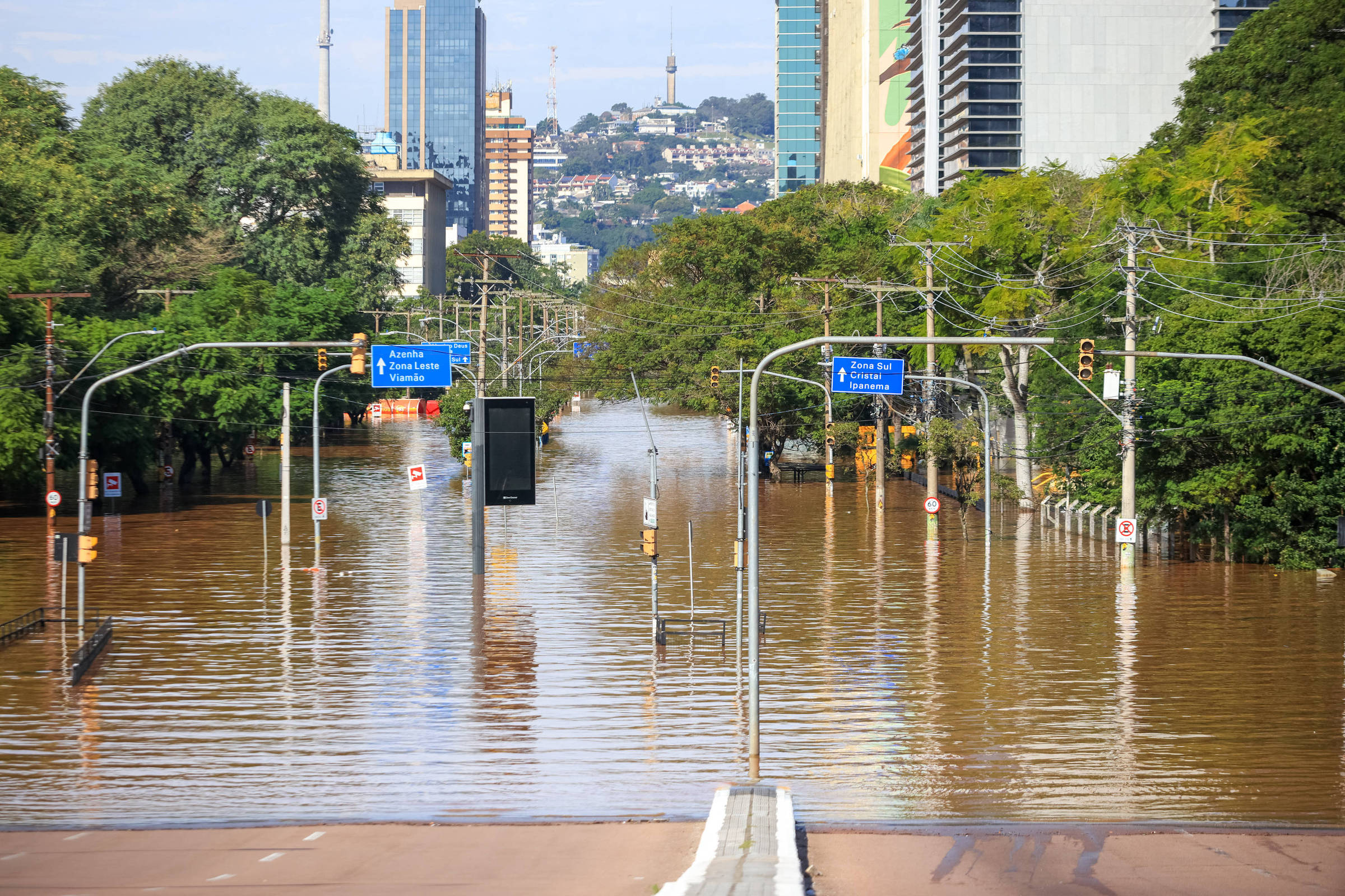 a flooded street with trees and buildings in the background