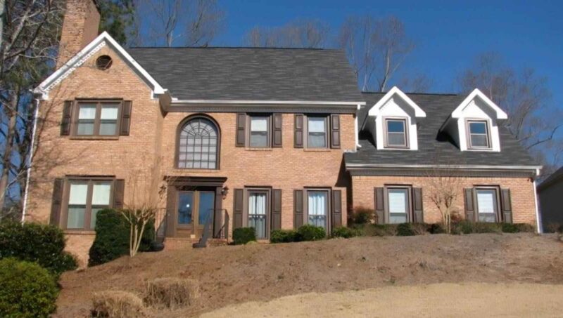 a large brick house with a hill in the background