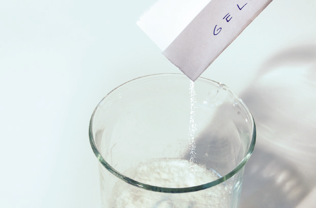 a hand pouring a white substance into a glass