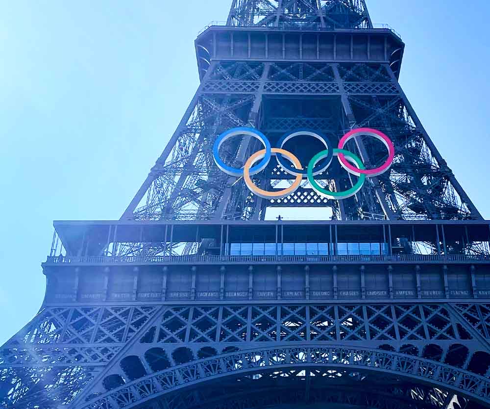 a large metal tower with olympic rings above it