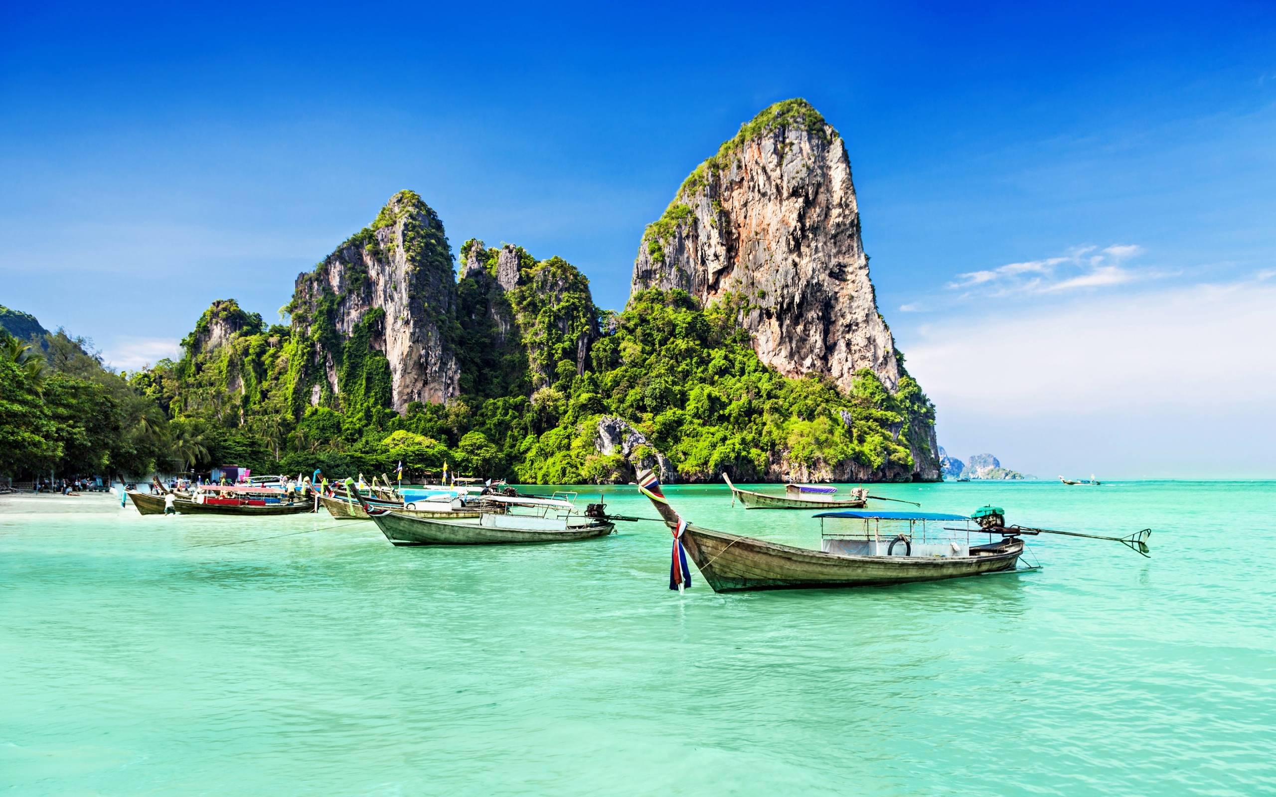 boats in the water with a large rock in the background with Railay Beach in the background