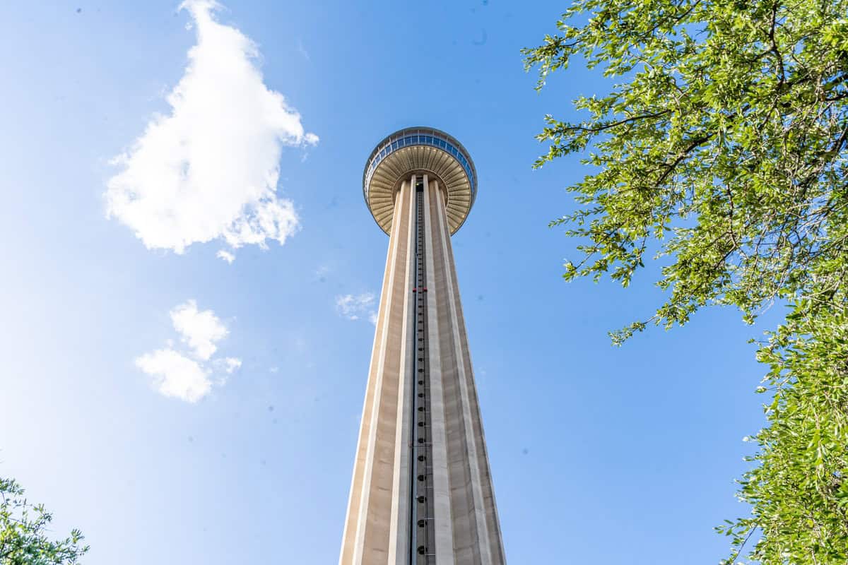 a tall tower with a round glass top with Tower of the Americas in the background