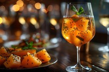 a glass of orange drink with fruit on a plate