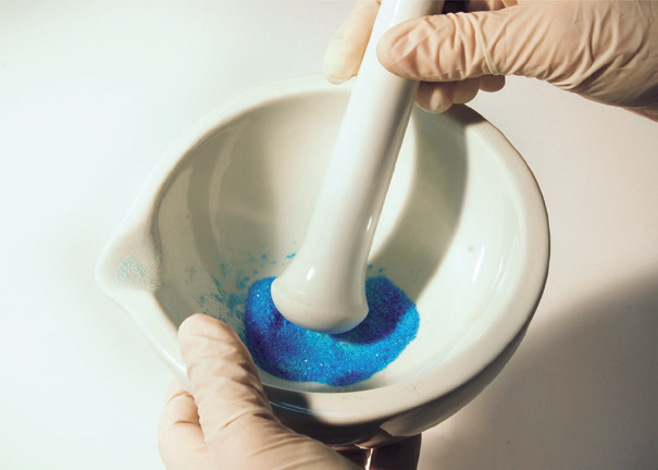 a person holding a mortar and pestle with blue powder