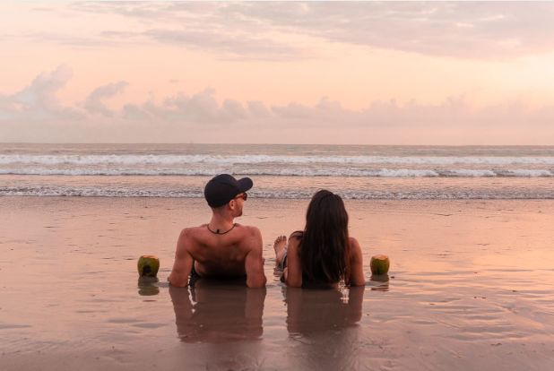 a man and woman sitting in the sand on a beach