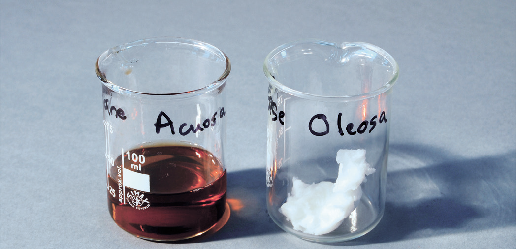 a close-up of a beaker with a brown liquid and a white object