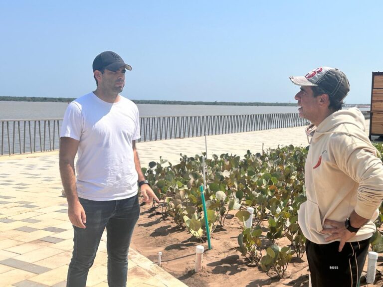 two men standing next to a plant