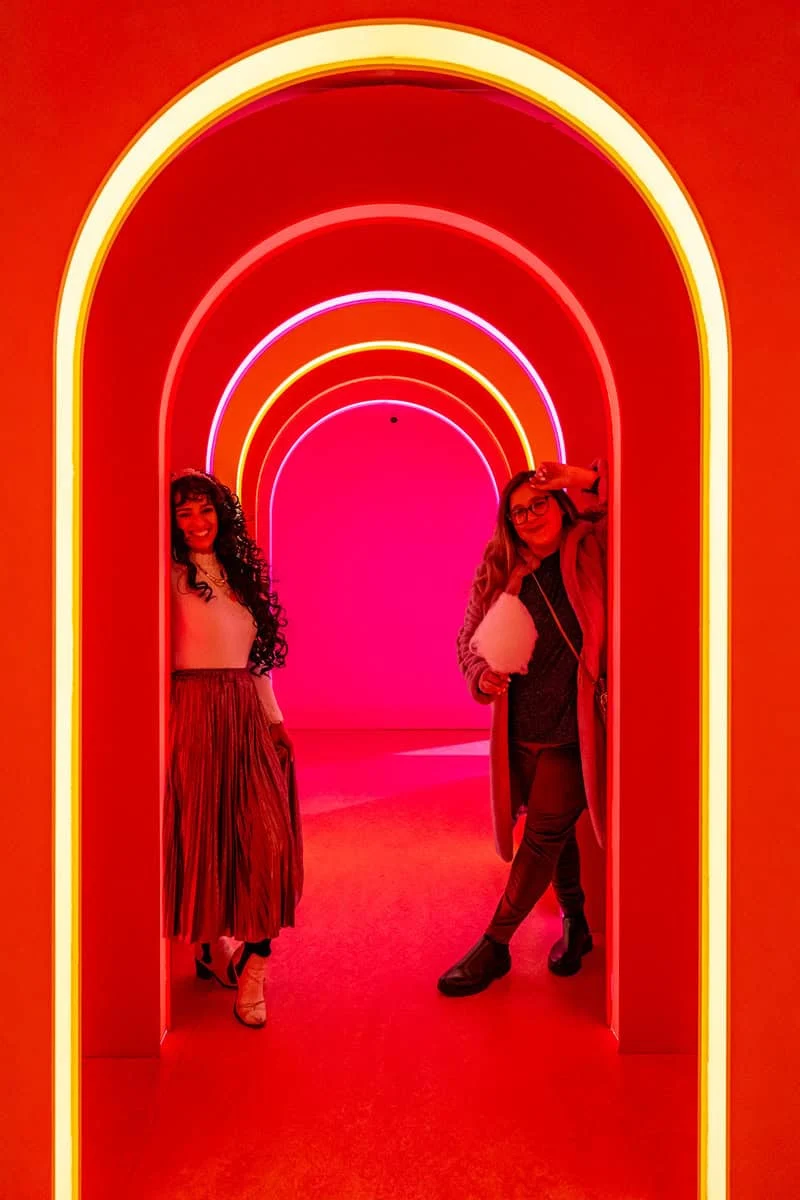 two women standing in a tunnel with neon lights