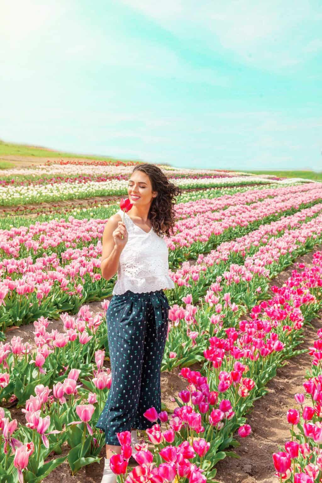 a woman standing in a field of pink and white flowers