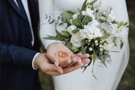 a person holding a bouquet of flowers and a wedding ring