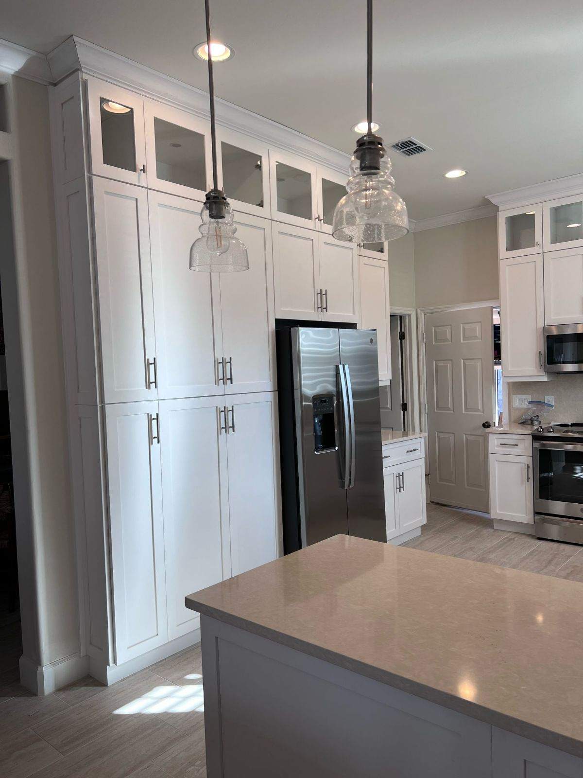 a kitchen with white cabinets and light fixtures
