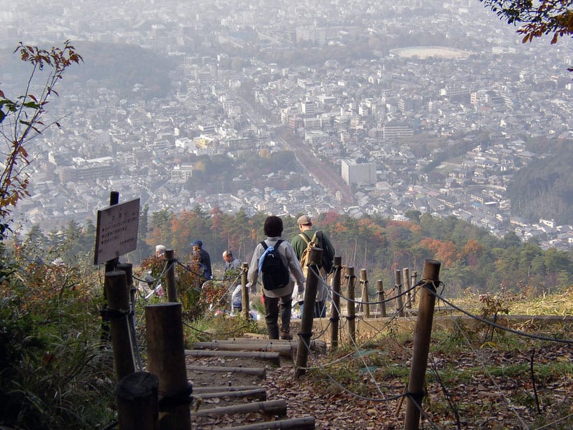 people walking up a hill with a city in the background