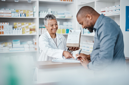 a woman in a white coat handing over a prescription to a man