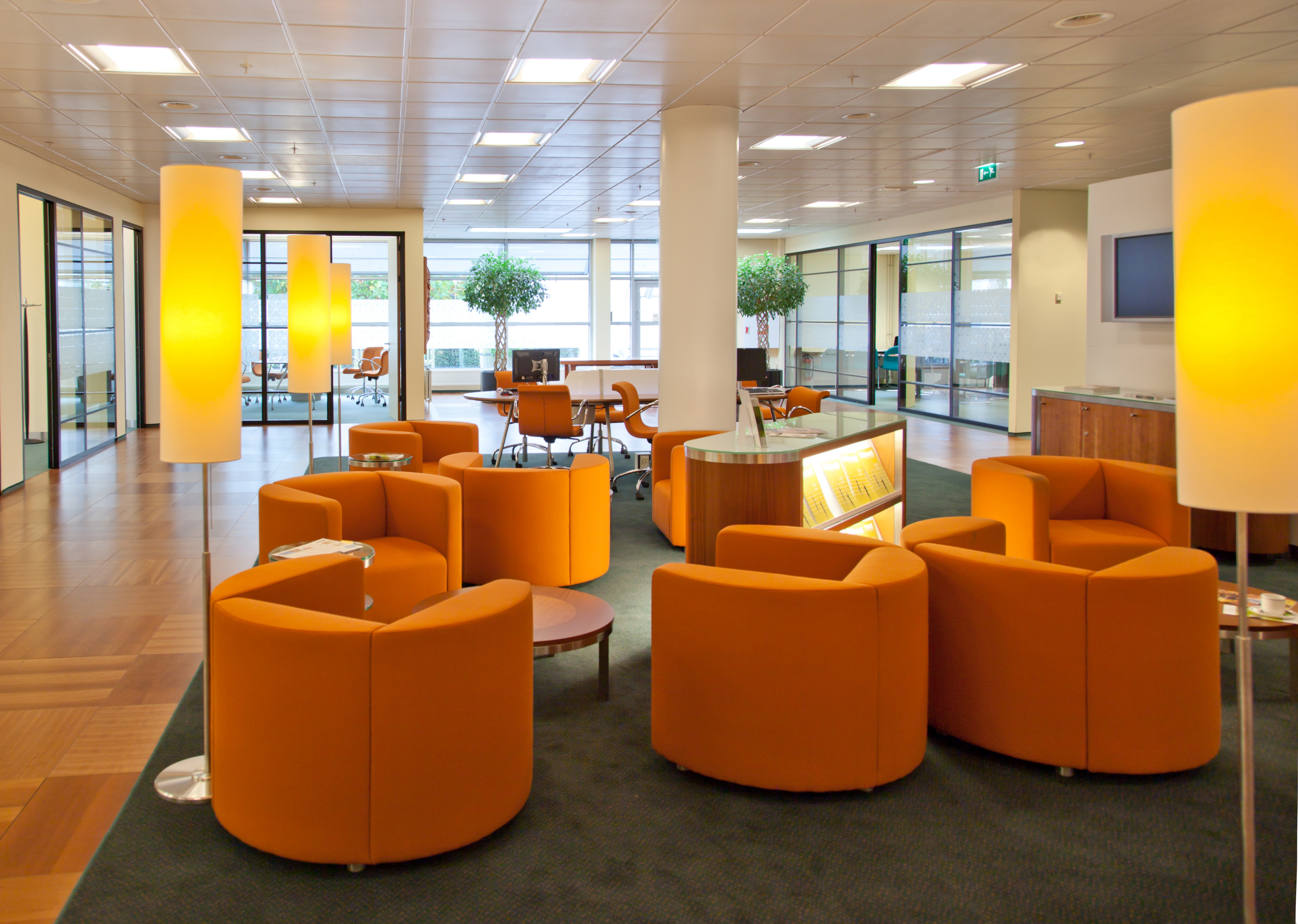 an office lobby with orange chairs and tables
