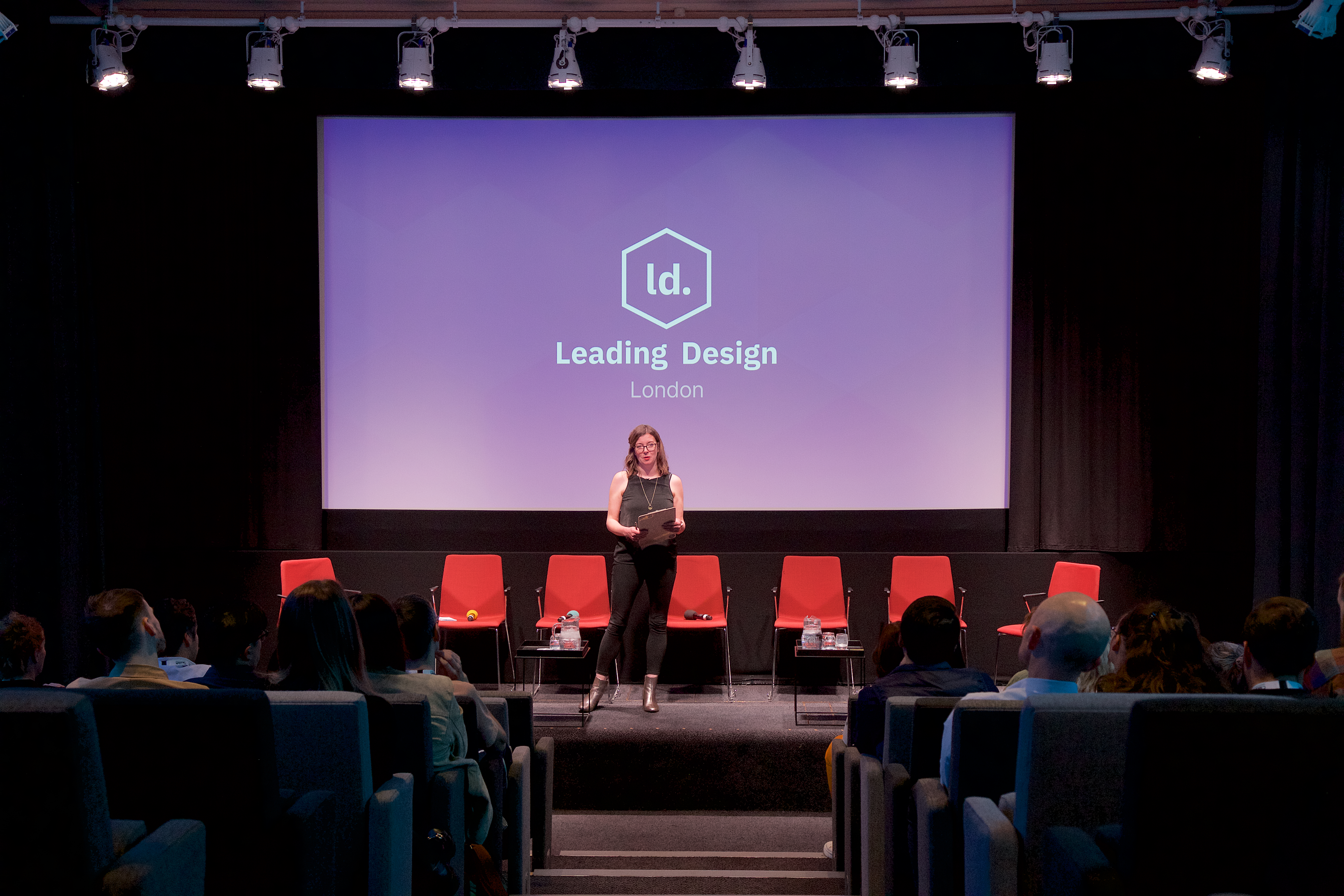 a woman standing on a stage in front of a large screen