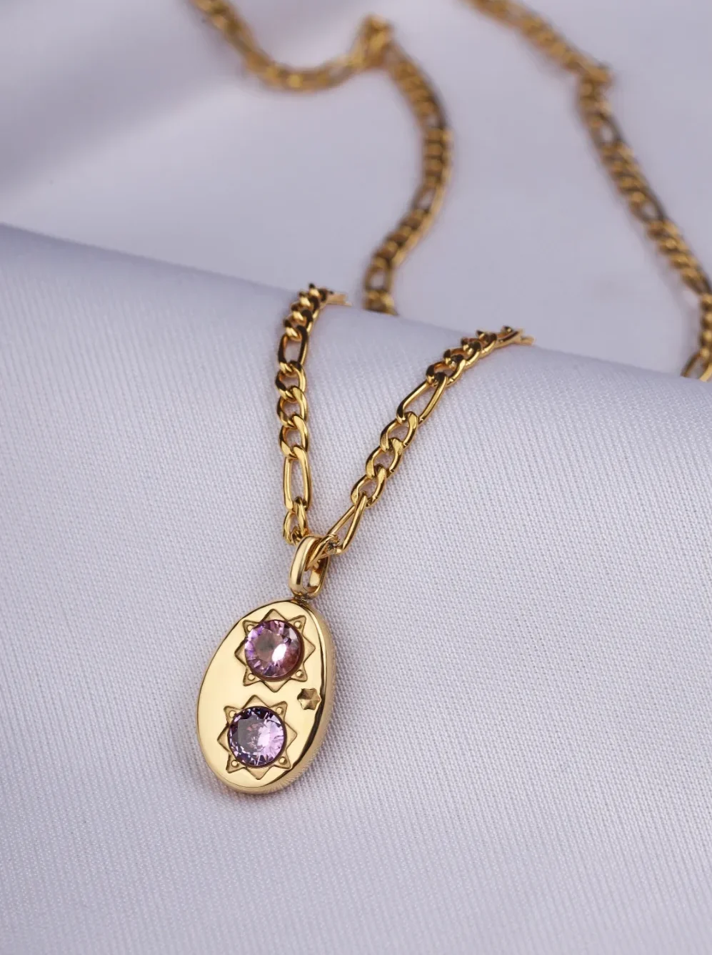 a gold necklace with a pendant and purple stones