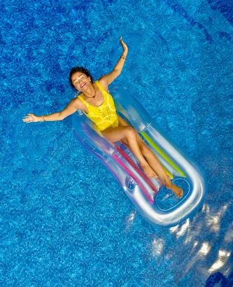 a woman floating on a floating raft in a pool