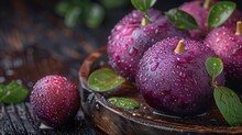 a group of purple apples on a wooden plate