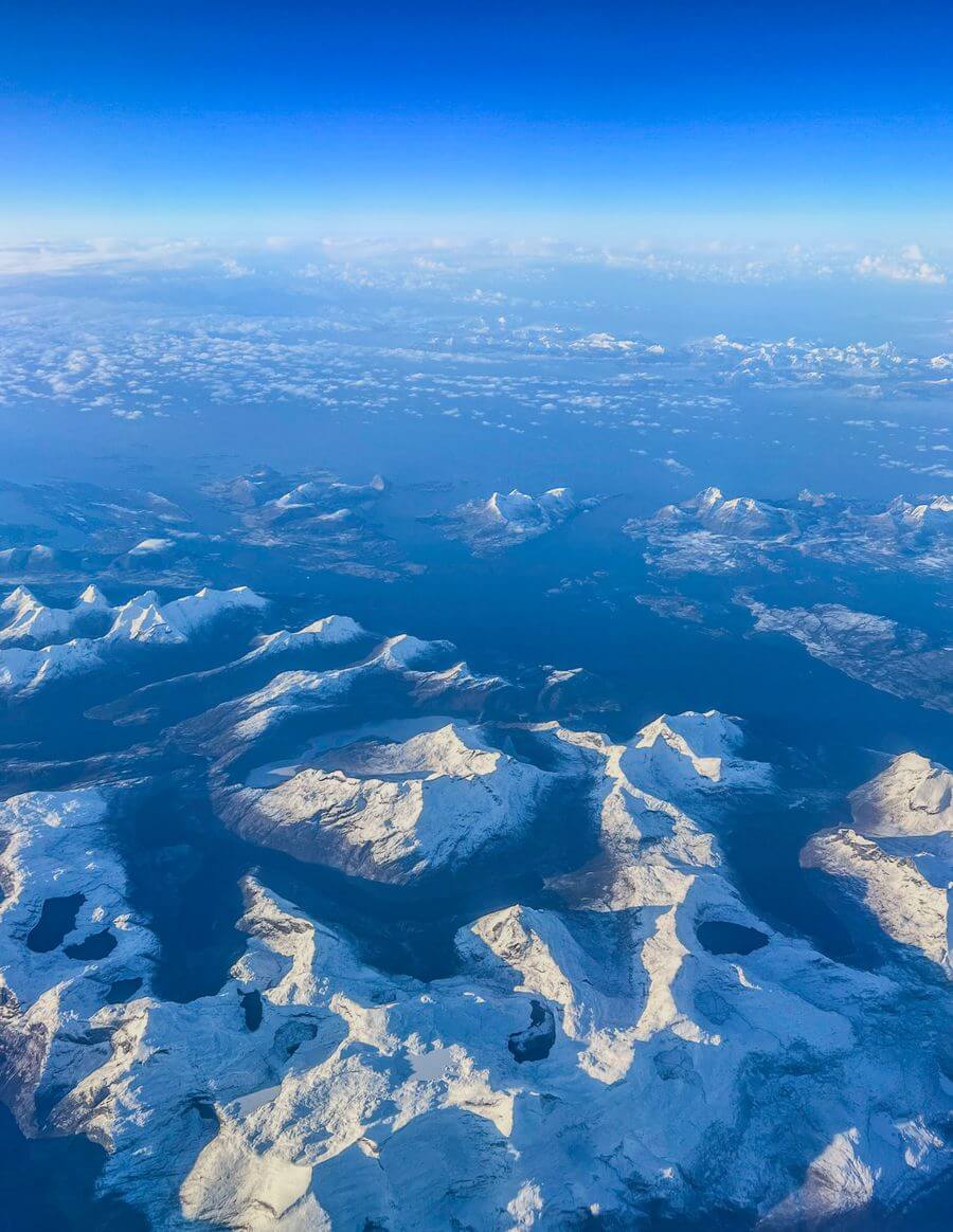 aerial view of snowy mountains and blue water