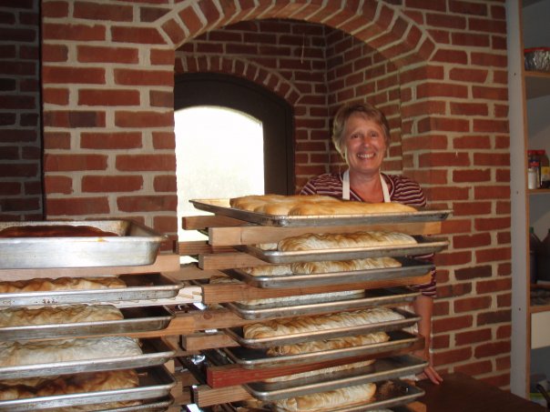 a woman standing next to trays of baked goods