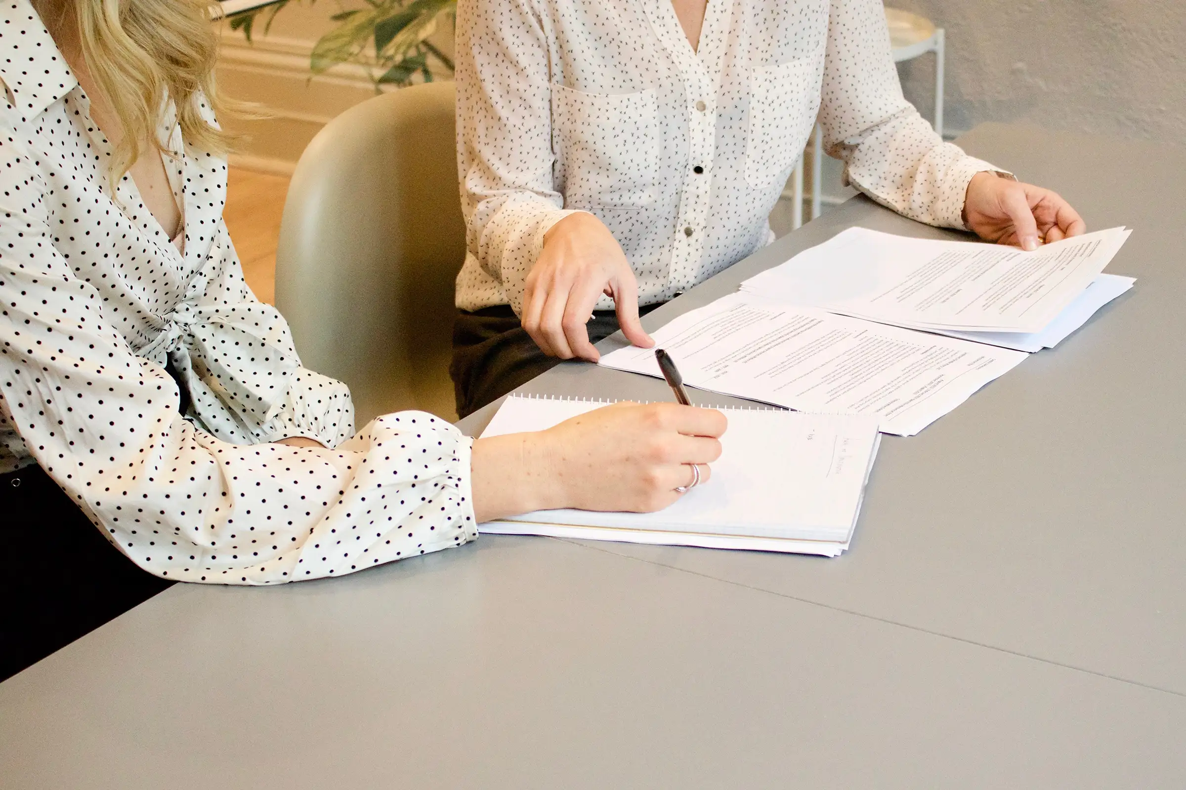 a woman sitting at a table writing on a notebook