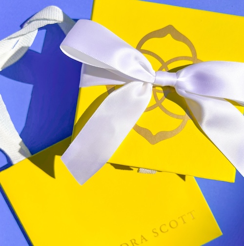 a yellow gift bag with a white bow