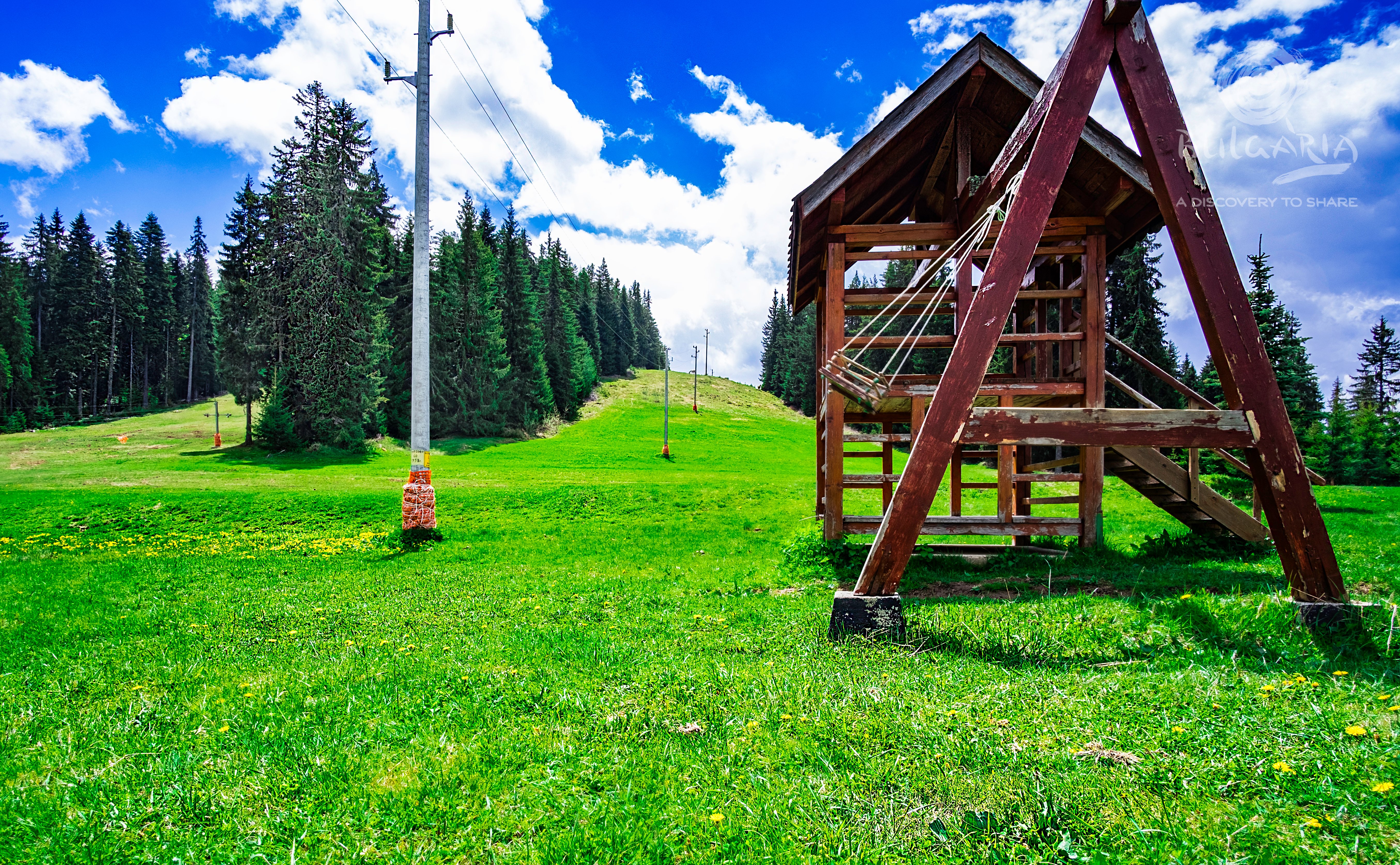 a wooden structure on a grassy hill