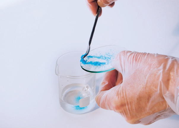 a hand holding a spoon with blue powder