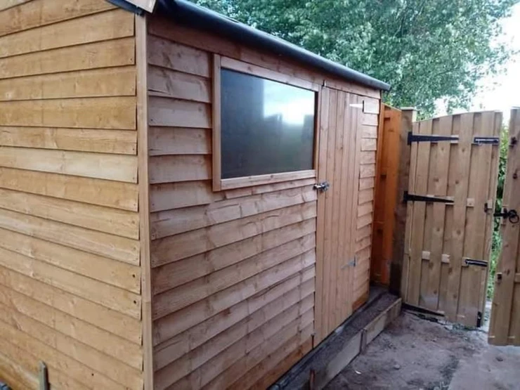 a wooden shed with a door and a gate