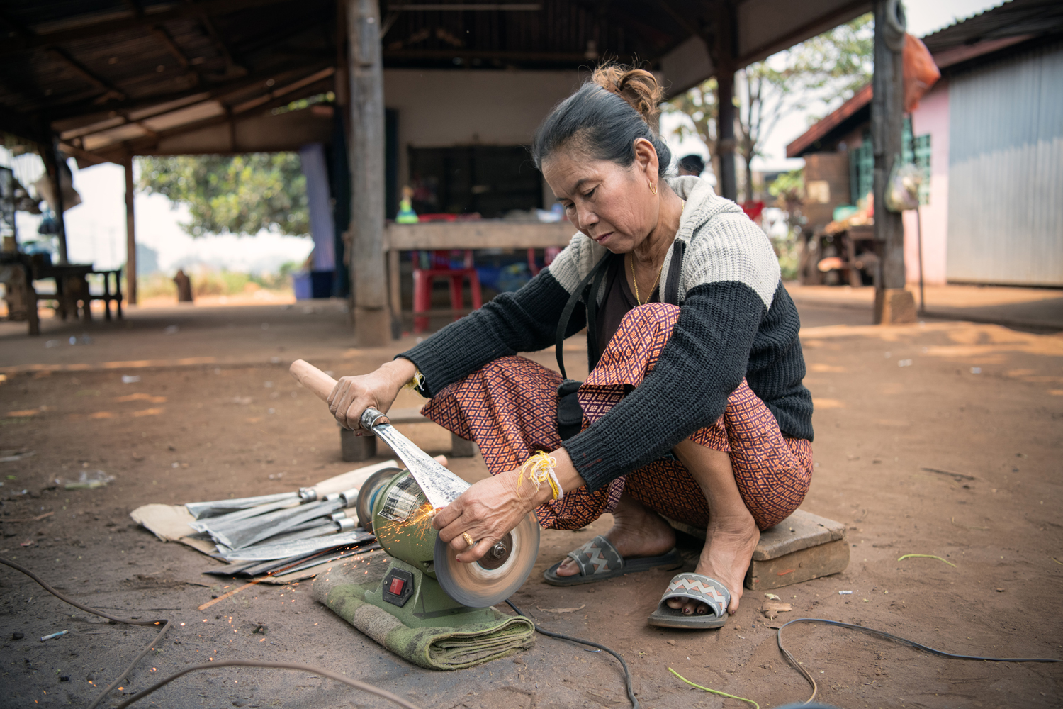 a woman using a knife to sharpen a metal object