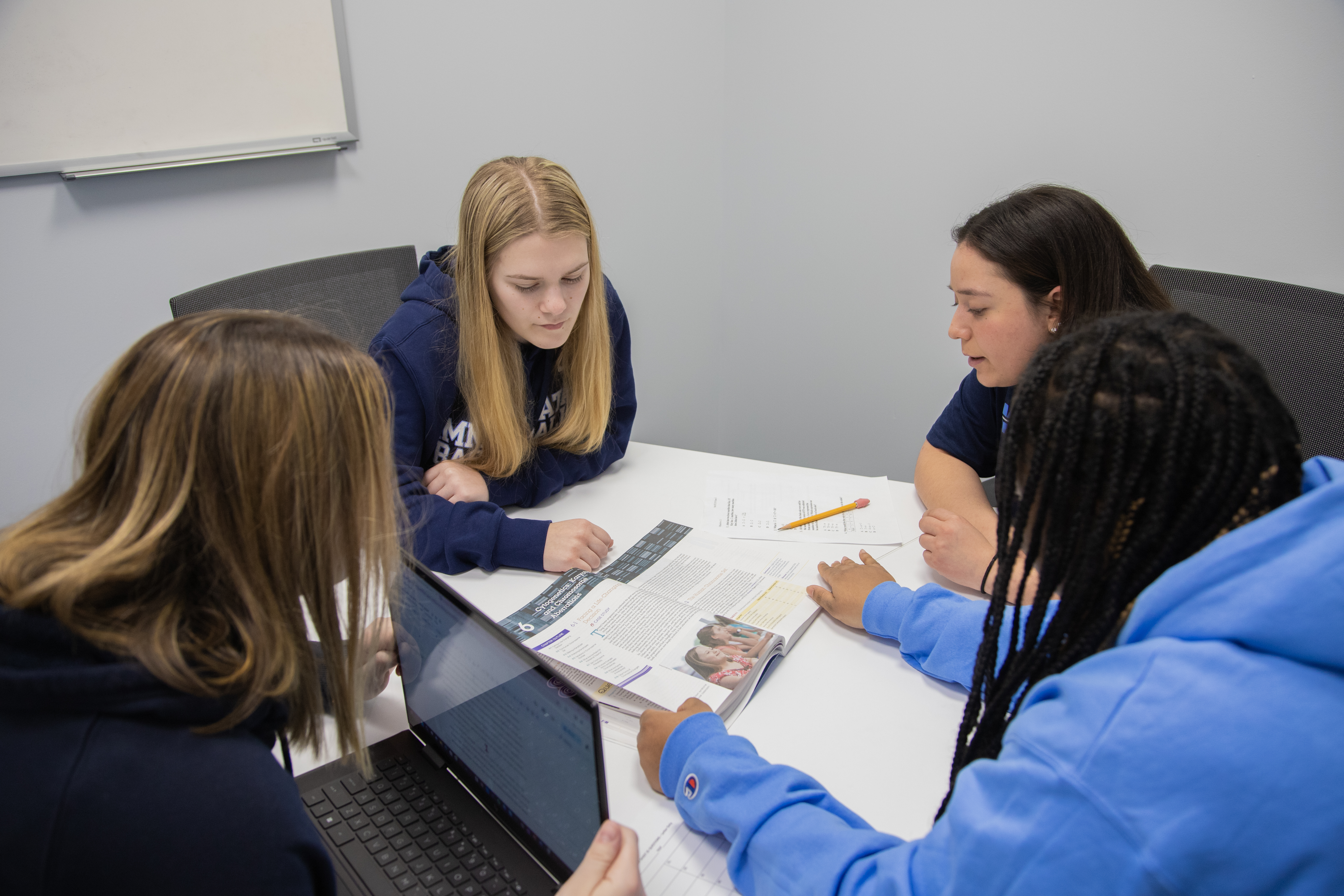 a group of women sitting at a table looking at a book